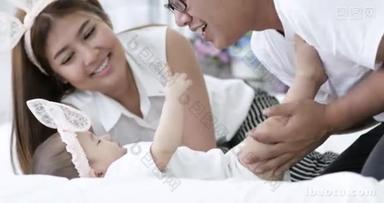 愉快的亚洲家庭婴孩与父母在家做乐趣以微笑的面孔.